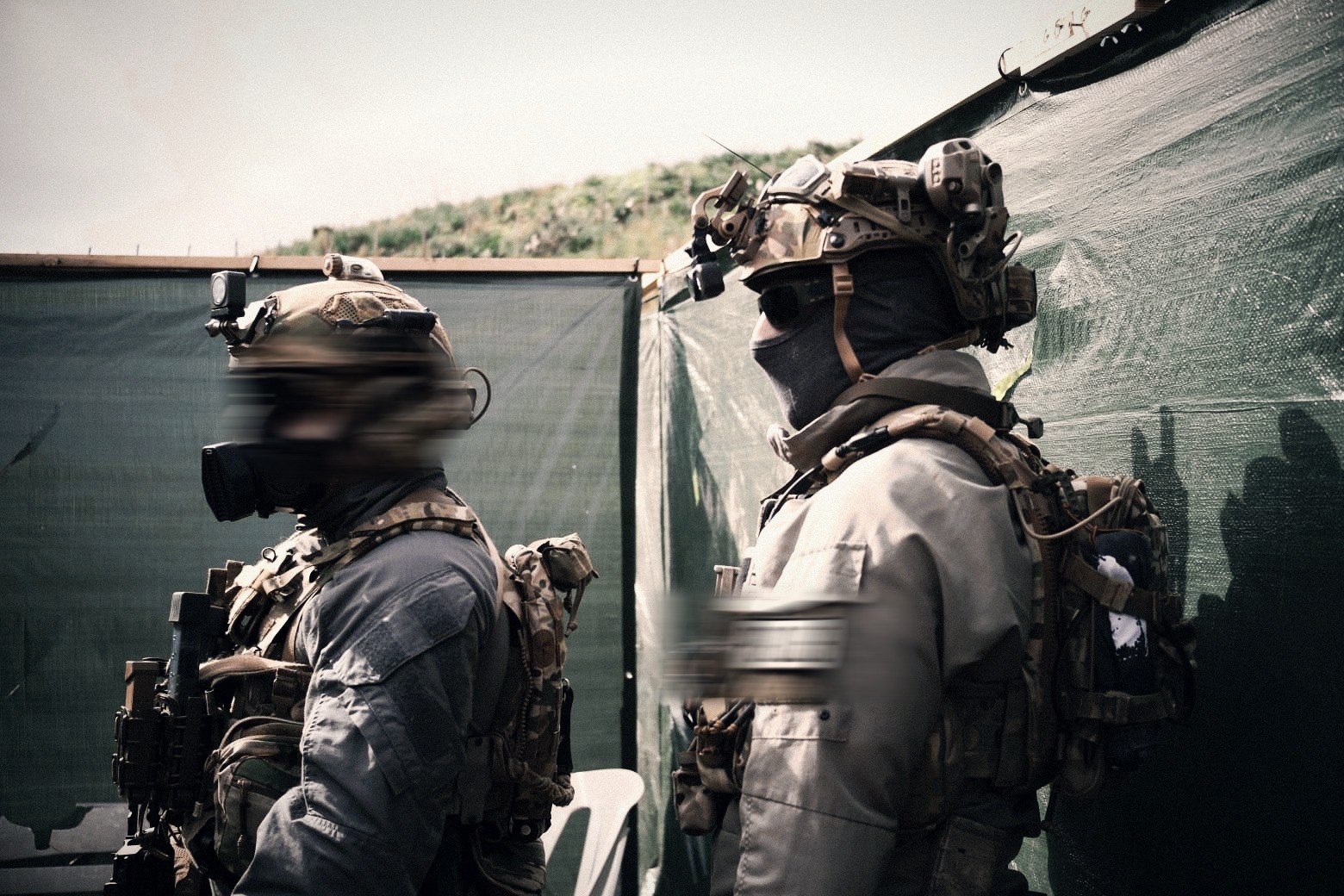 Operators in protective masks and tactical kit during outdoor live-fire training
